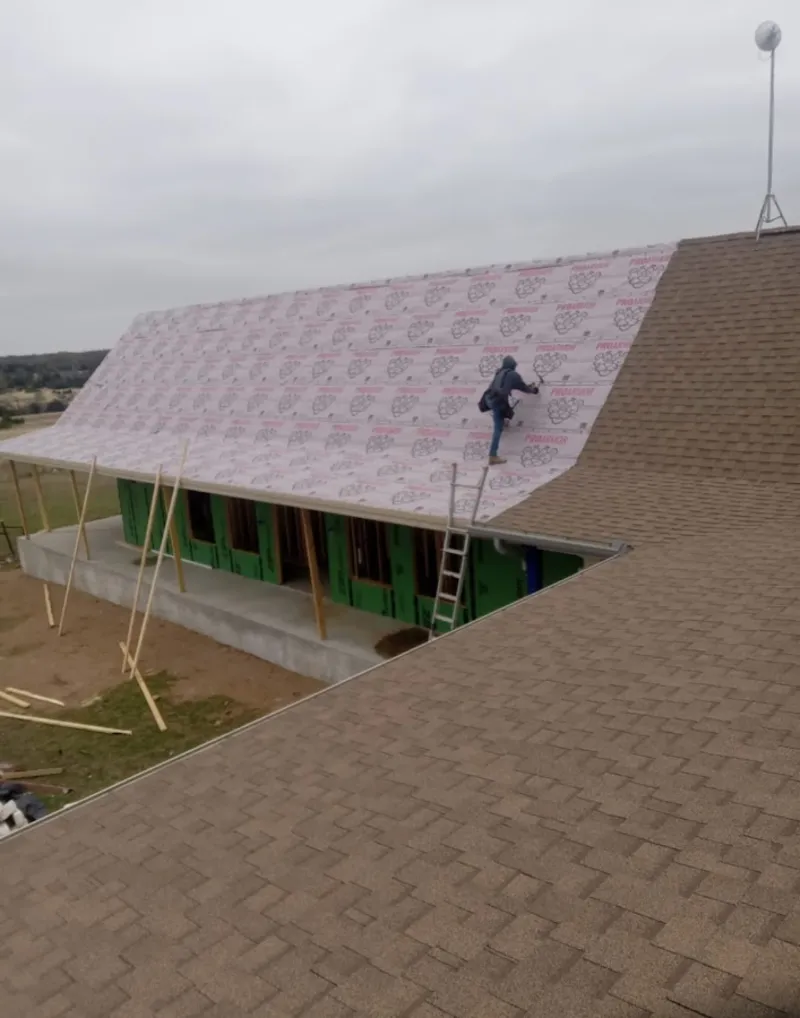 Worker preparing underlayment for a metal roof installation in Makakilo